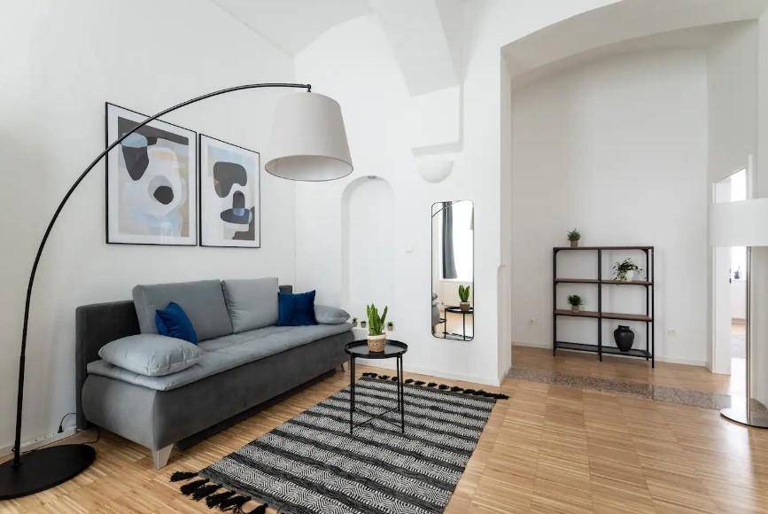 Wohnbereich mit bequemem Sofa, stilvoller Bogenlampe und dekorativem Spiegel, offen gestaltet.
