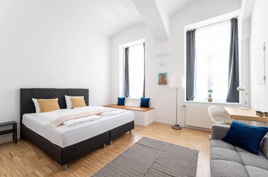 Helles Schlafzimmer mit Doppelbett, Schreibtisch und gemütlicher Fensterbank, modern eingerichtet.