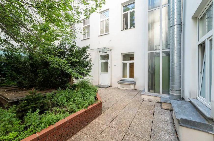 Begrünter Innenhof mit gepflastertem Bereich und Zugang zum Gebäude, ruhig gelegen.