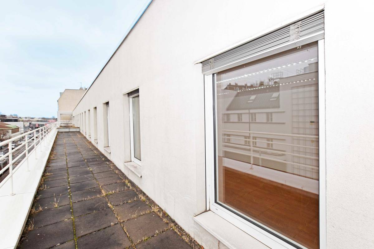 Lange, gepflasterte Dachterrasse mit Geländer und Blick auf die Stadt, ideal für Pausen im Freien.