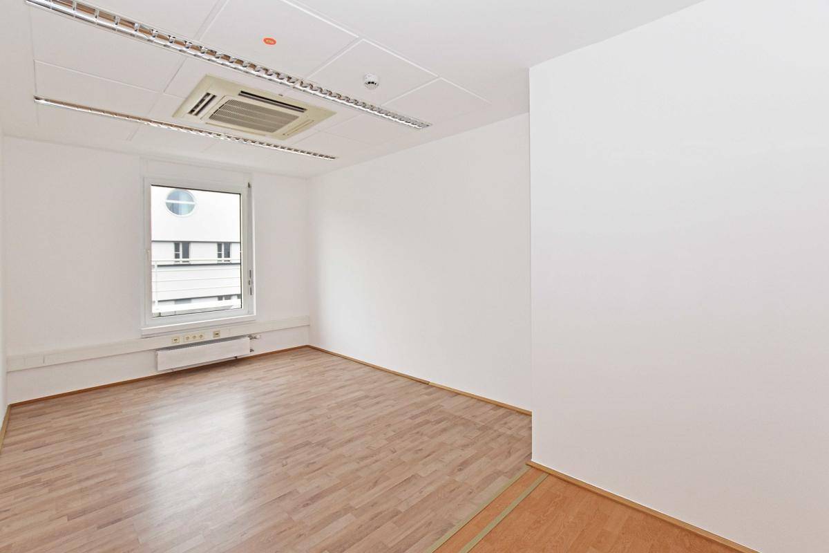 Helles Büro mit einem runden Fenster und Blick auf die Stadt, ausgestattet mit Klimaanlage und Laminatboden.