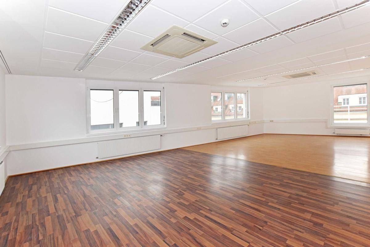 Großes, offenes Büro mit zwei verschiedenen Laminatböden und Deckenbeleuchtung, ideal für Großraumbüros.