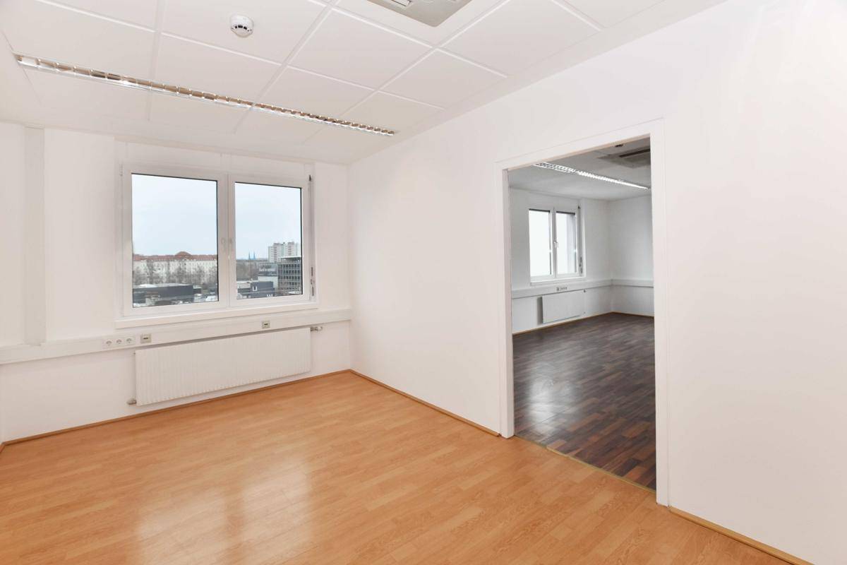 Helles Büro mit Blick auf die Stadt, verbunden mit einem weiteren Raum, ausgestattet mit Klimaanlage und Laminatboden.