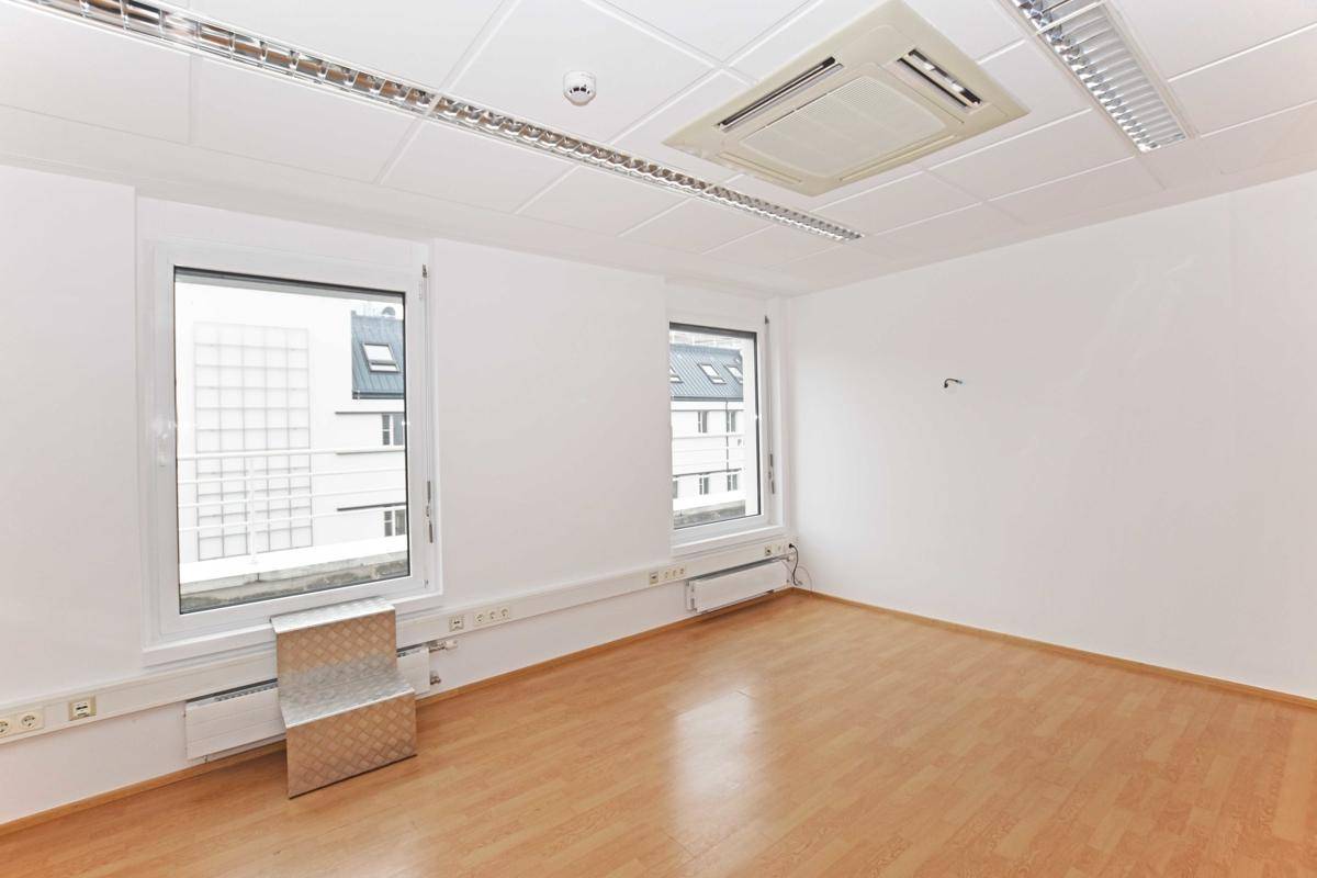 Helles Büro mit zwei Fenstern und Blick auf die Stadt, ausgestattet mit Klimaanlage und Laminatboden.