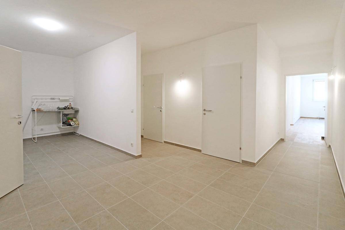 Heller Flur mit Fliesenboden und mehreren Türen, der zu verschiedenen Bereichen des Gebäudes führt.