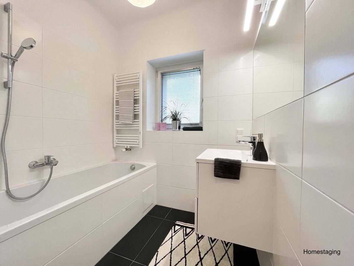 Modernes Badezimmer mit Badewanne, Waschbecken und beheiztem Handtuchhalter.