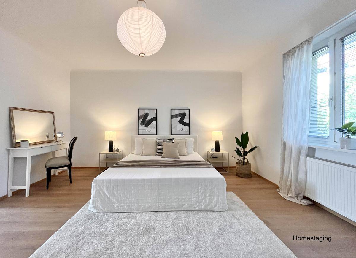 Modern eingerichtetes Schlafzimmer mit hellem Laminatboden, großem Bett und Fenster.
