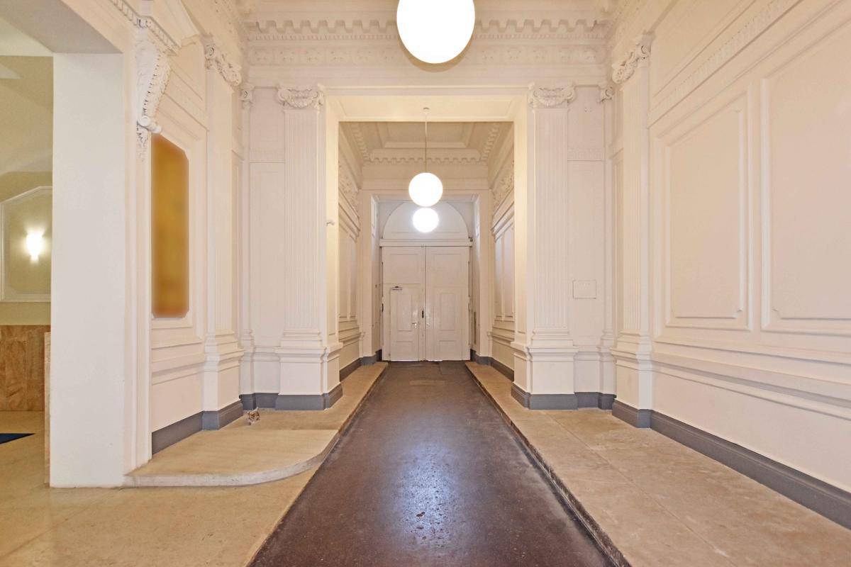 Prächtiger Flur mit hohen Decken, dekorativen Säulen und eleganten Wandverkleidungen, beleuchtet von modernen Pendelleuchten.