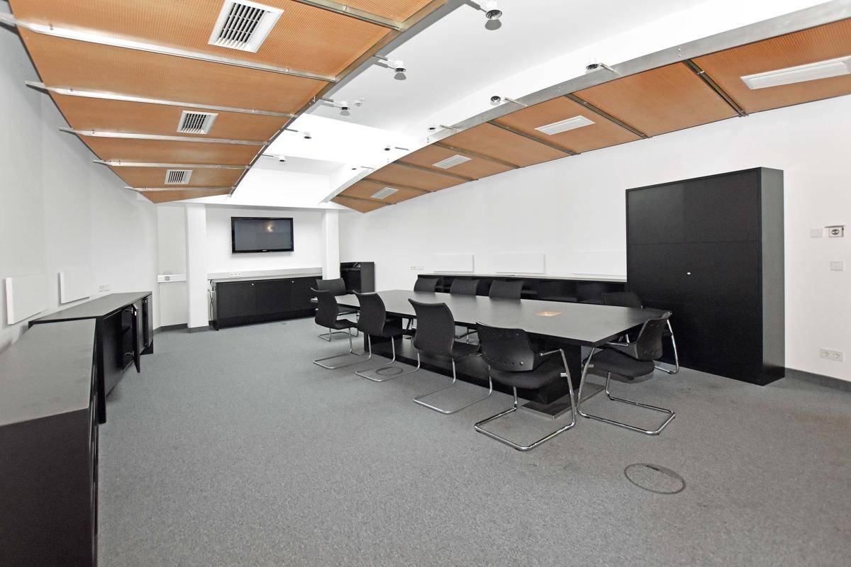 Konferenzraum mit großem Tisch, bequemen Stühlen und einer modernen Deckenverkleidung.