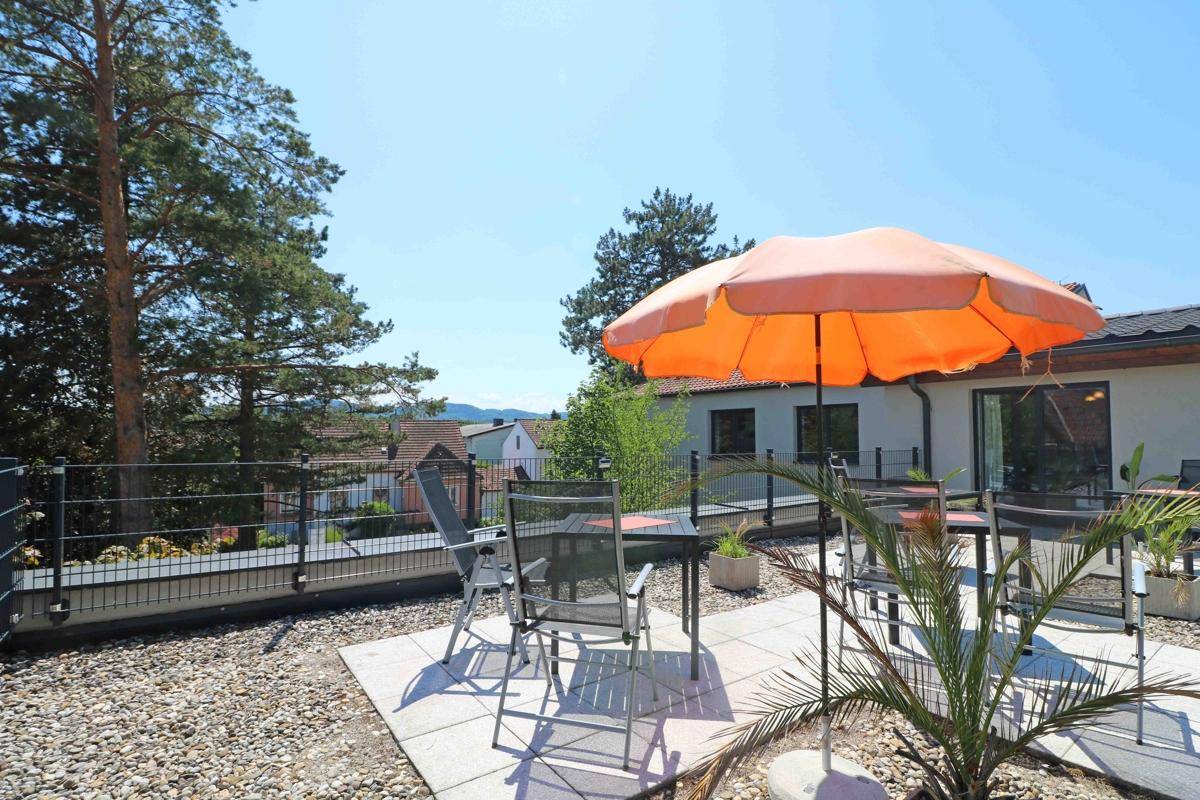 Große Dachterrasse mit Sitzgelegenheiten, Sonnenschirm und weitem Blick über die Umgebung.