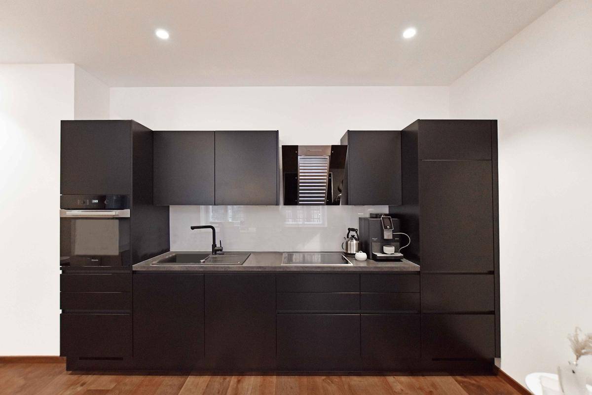 Moderne schwarze Einbauküche mit integrierten Geräten und minimalistischem Design, perfekt für eine stilvolle Wohnung.
