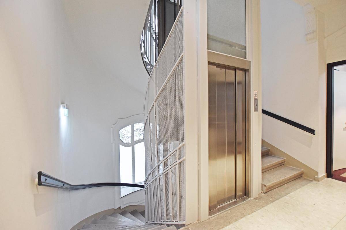 Elegantes Treppenhaus mit einer modernen Aufzugsanlage, die den Zugang zu den Etagen erleichtert.