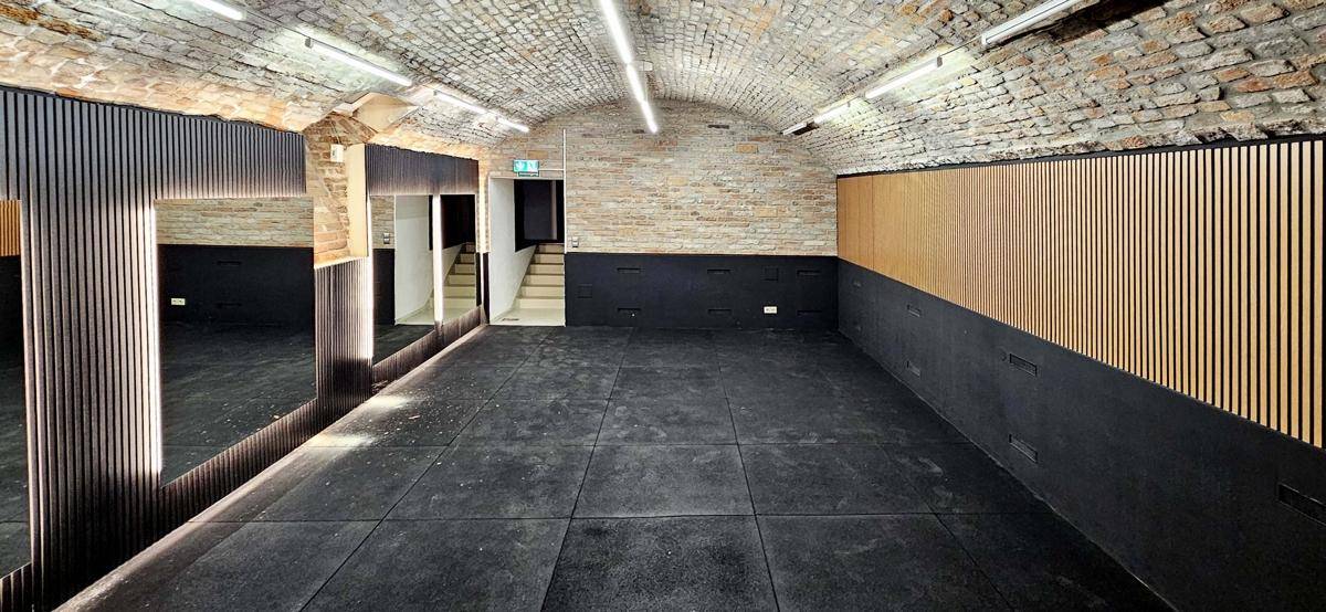 Gewölbekeller mit unverputzten Ziegelwänden, dunklem Boden und modernen Holzvertäfelungen, stilvoll renoviert.