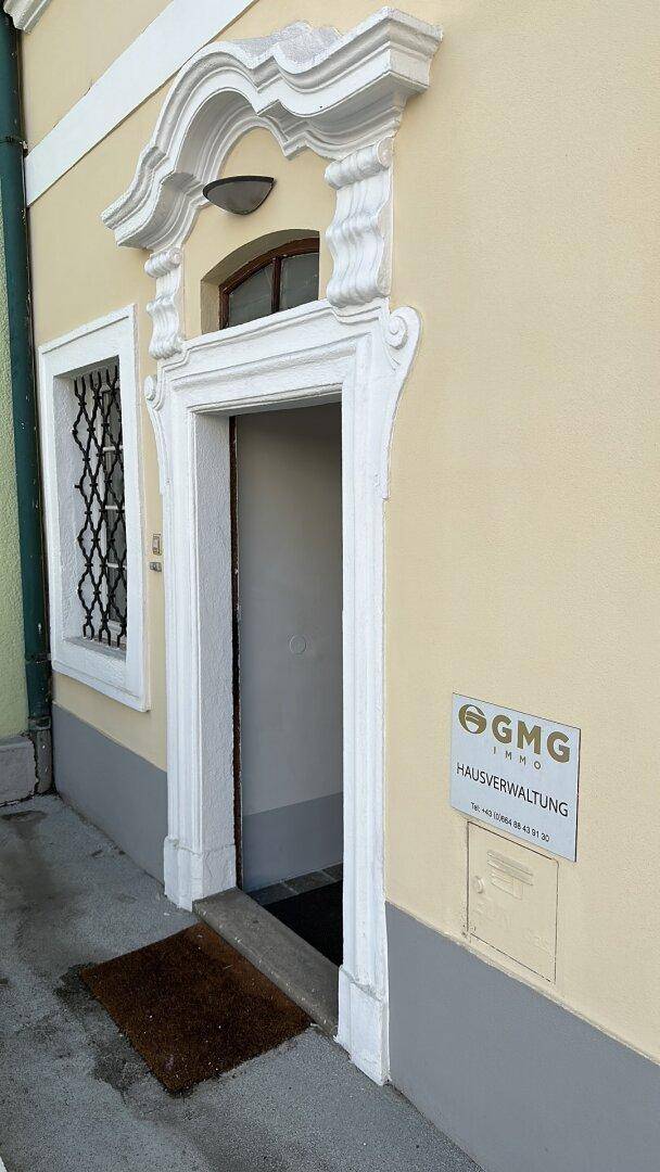 Verzierter Eingangsbereich eines gepflegten Altbaus mit heller Fassade und klassischen Details.