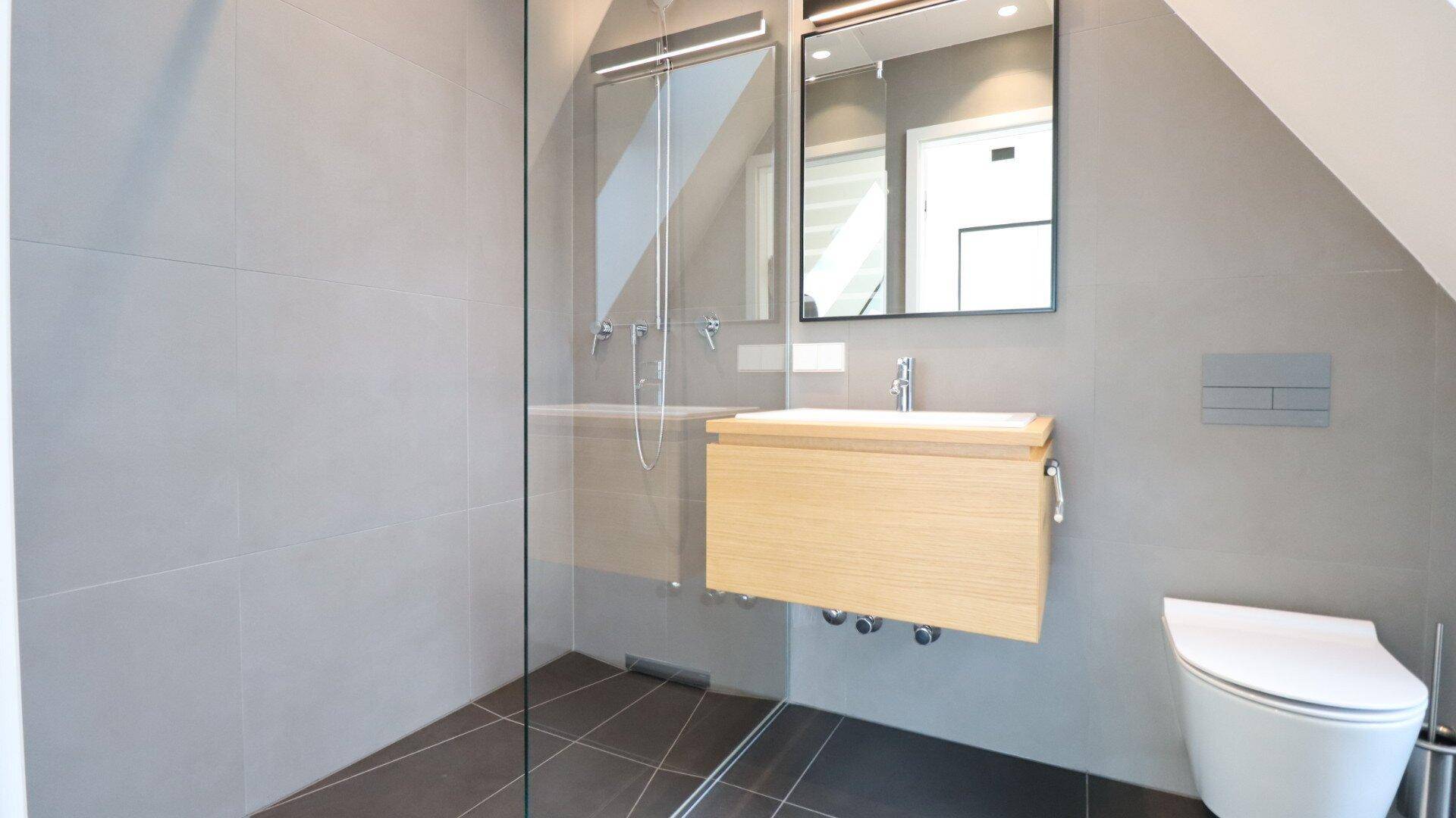 Modernes Badezimmer mit begehbarer Dusche, Einzelwaschbecken und wandhängendem WC.