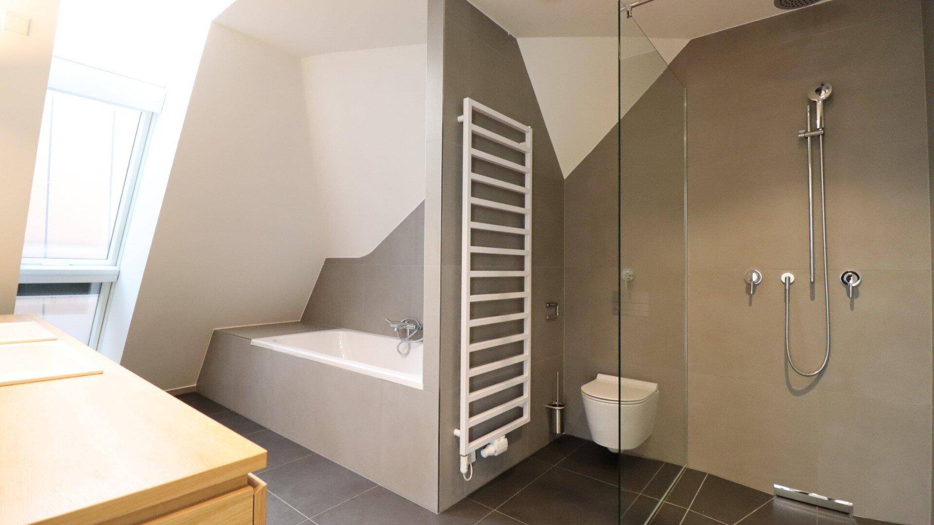Elegantes Badezimmer mit begehbarer Dusche, Badewanne, WC und beheiztem Handtuchhalter.
