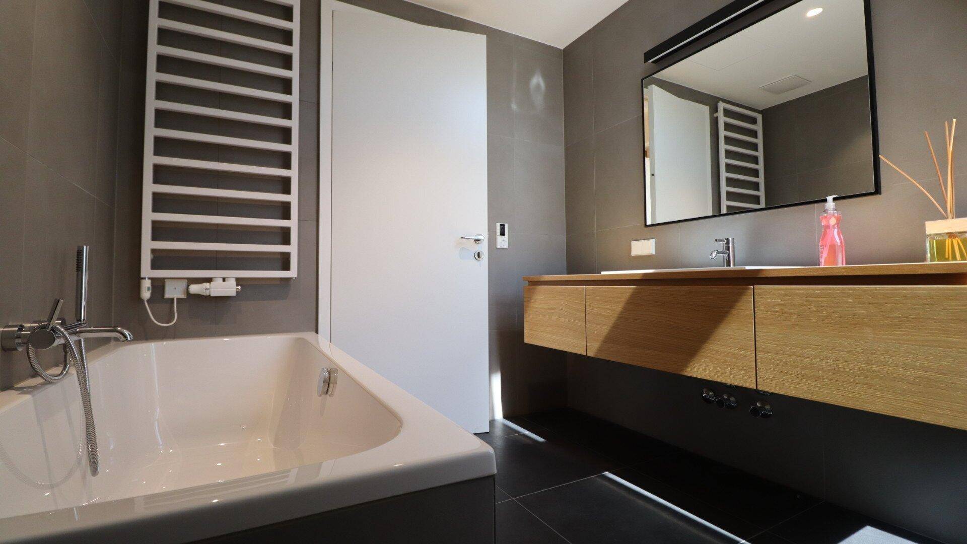 Modernes Badezimmer mit Badewanne, Einzelwaschbecken und beheiztem Handtuchhalter.