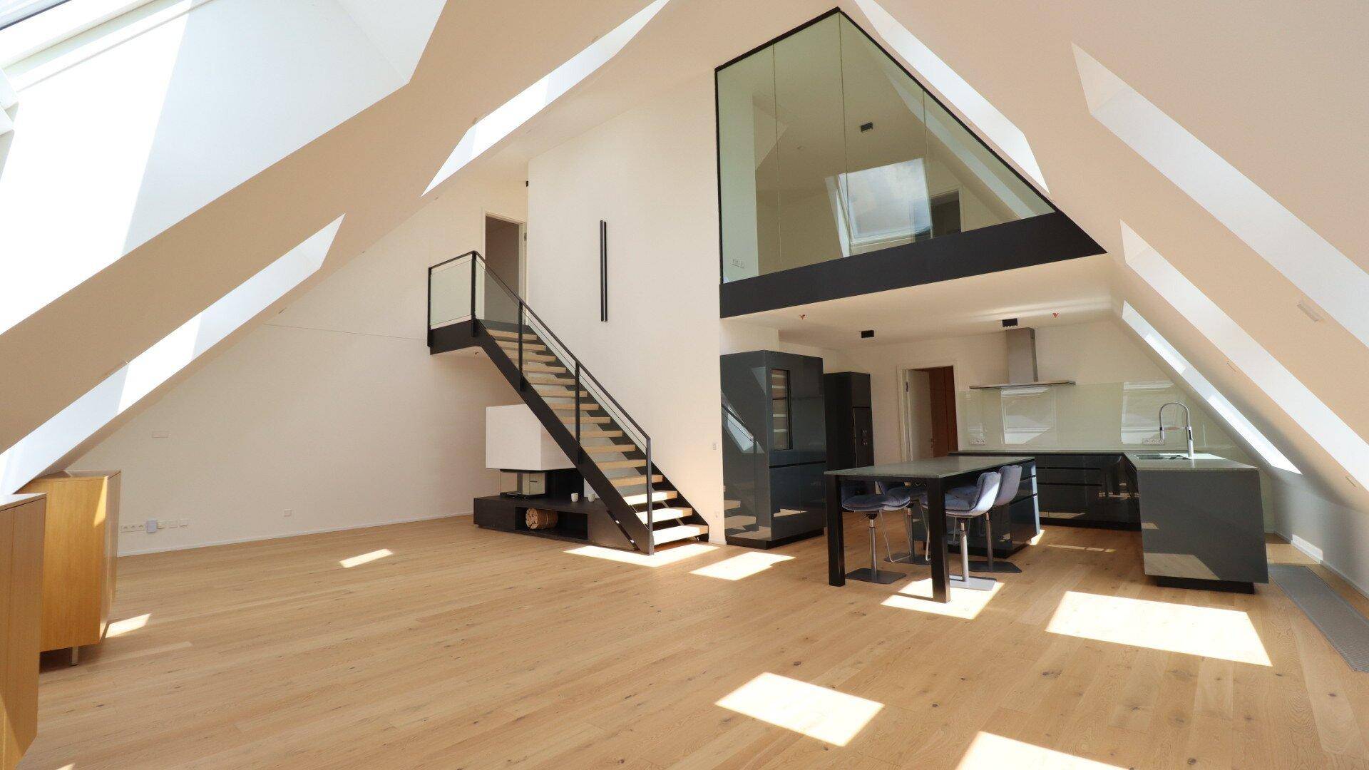 Geräumiges Dachgeschoss-Loft mit offener Küche, Essbereich und moderner Treppe.