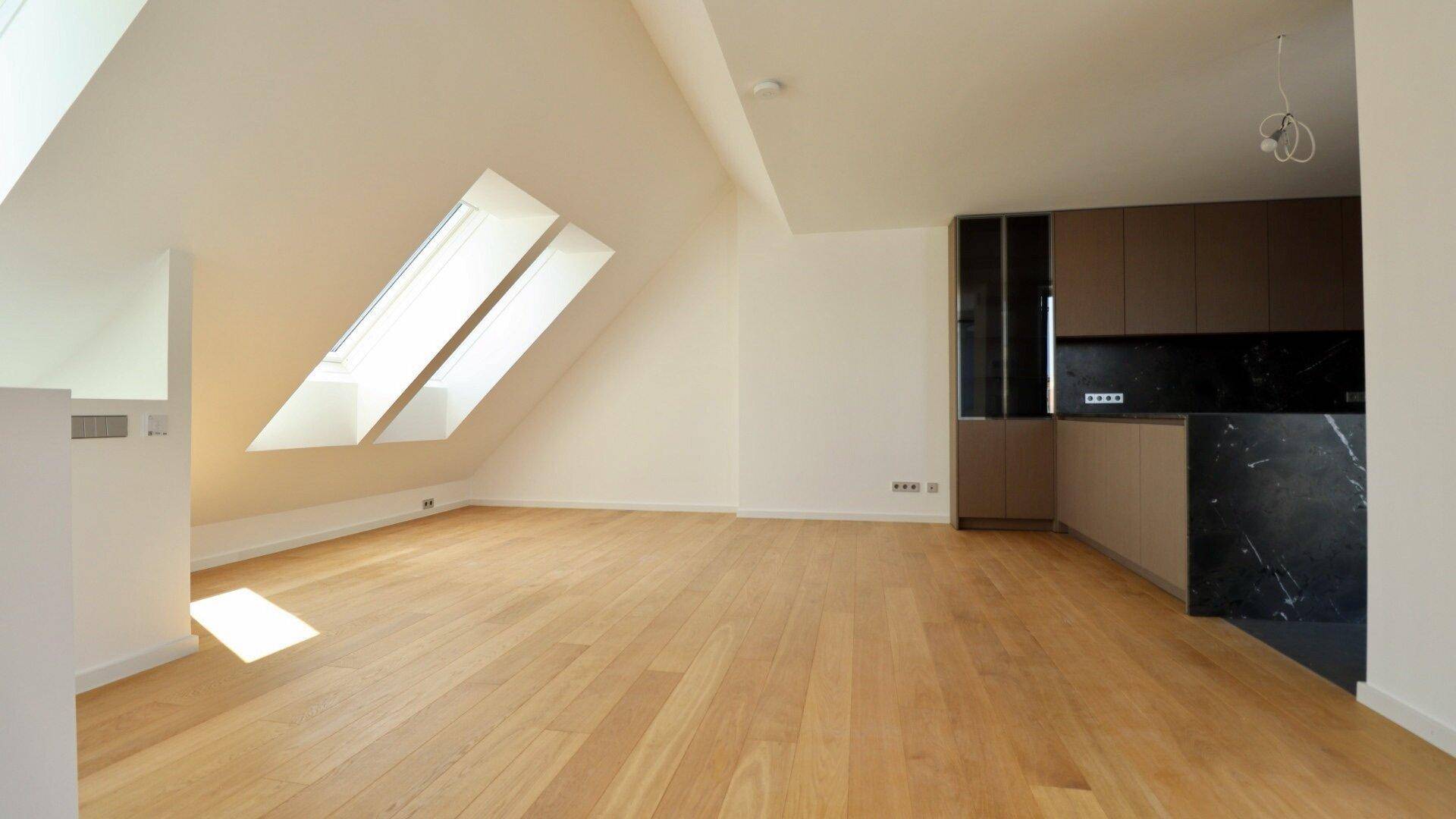 Lichtdurchfluteter Wohnbereich im Dachgeschoss mit Holzboden, Dachschrägen und modernen Dachfenstern.
