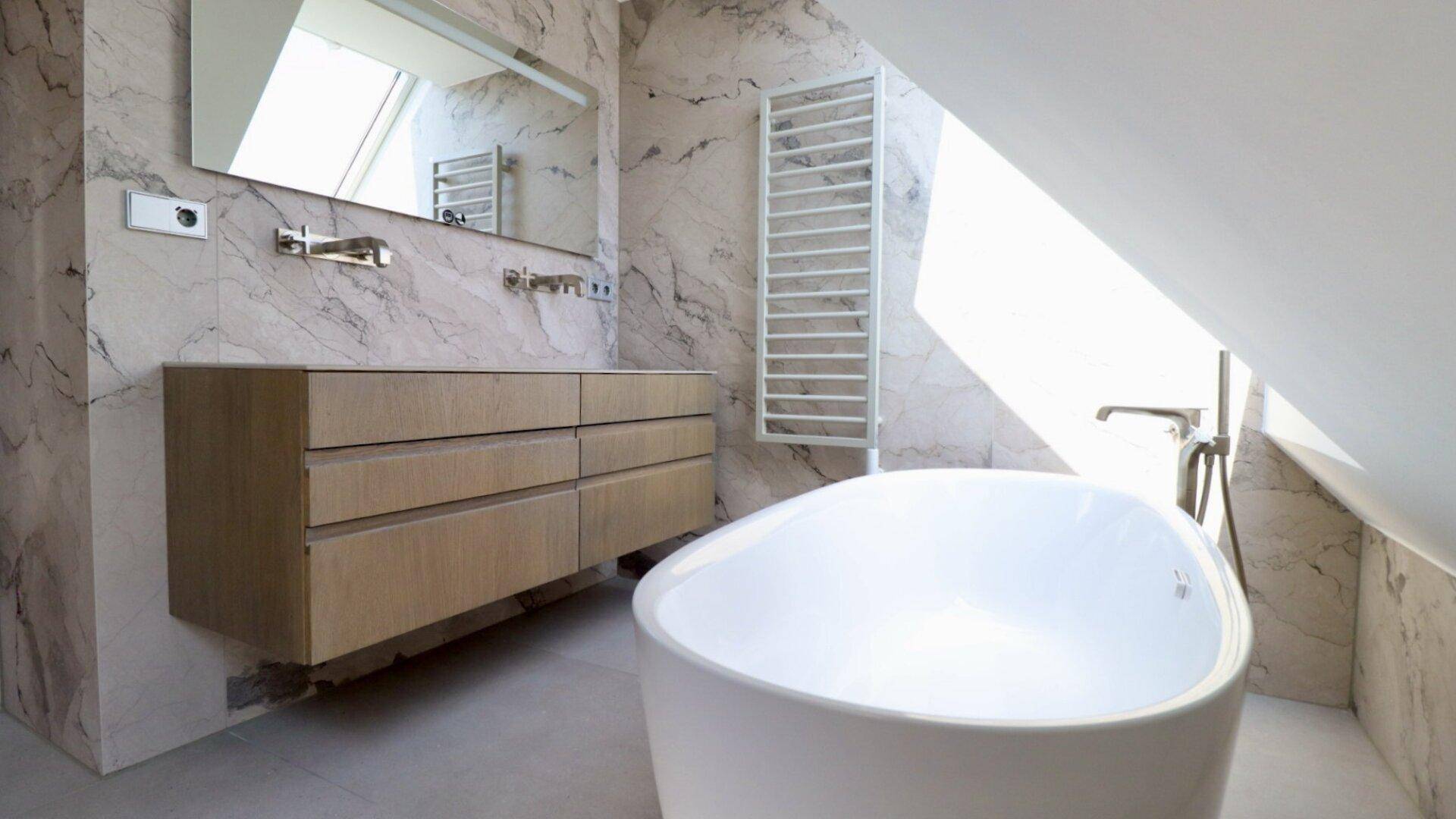 Modernes Badezimmer im Dachgeschoss mit freistehender Badewanne, Marmorfliesen und Dachfenster.