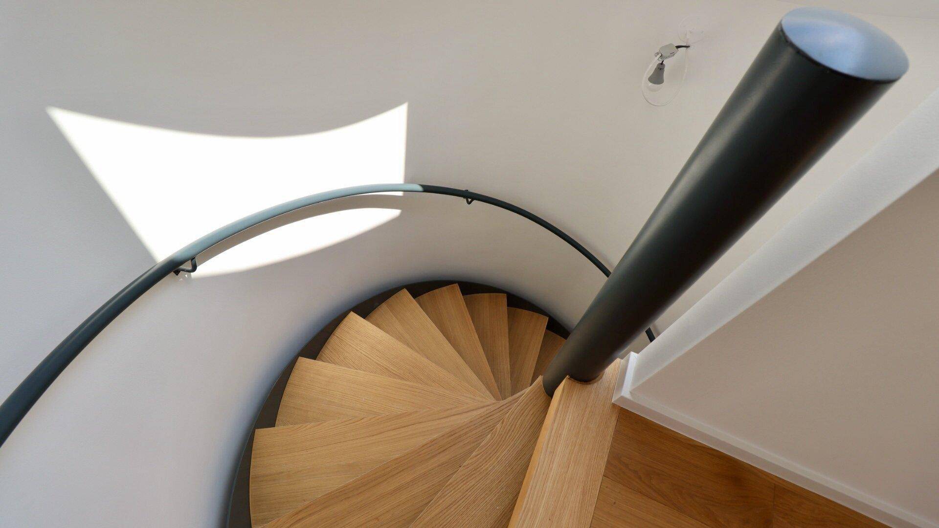 Elegante Holzwendeltreppe mit modernem Geländer, die die verschiedenen Ebenen des Hauses verbindet.