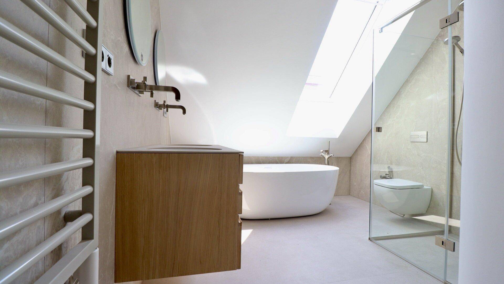 Modernes Badezimmer im Dachgeschoss mit Dusche, freistehender Badewanne und beheiztem Handtuchhalter.