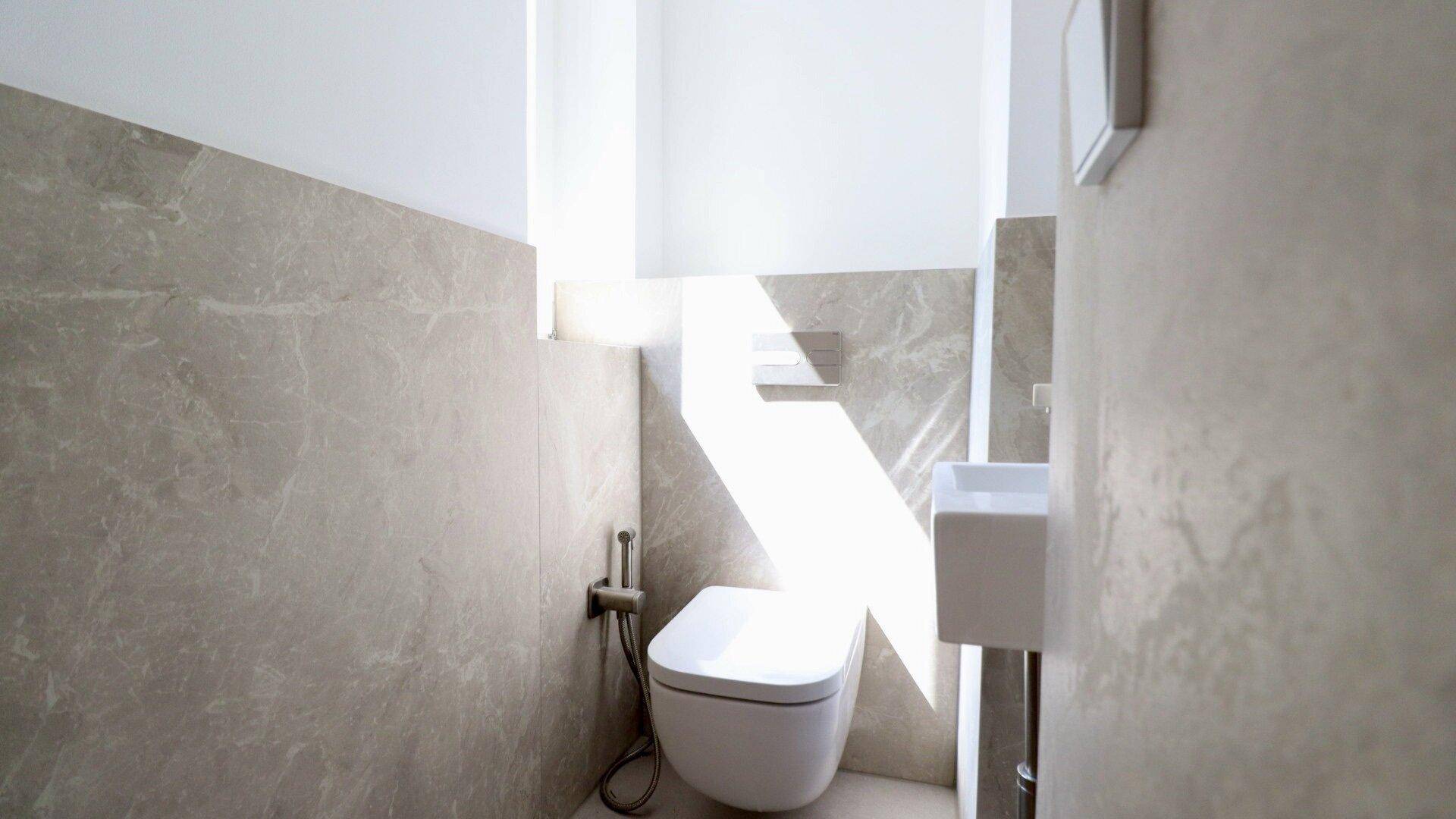 Modernes Gäste-WC mit Wand-WC, kleinem Waschbecken und stilvollen Fliesen an den Wänden.