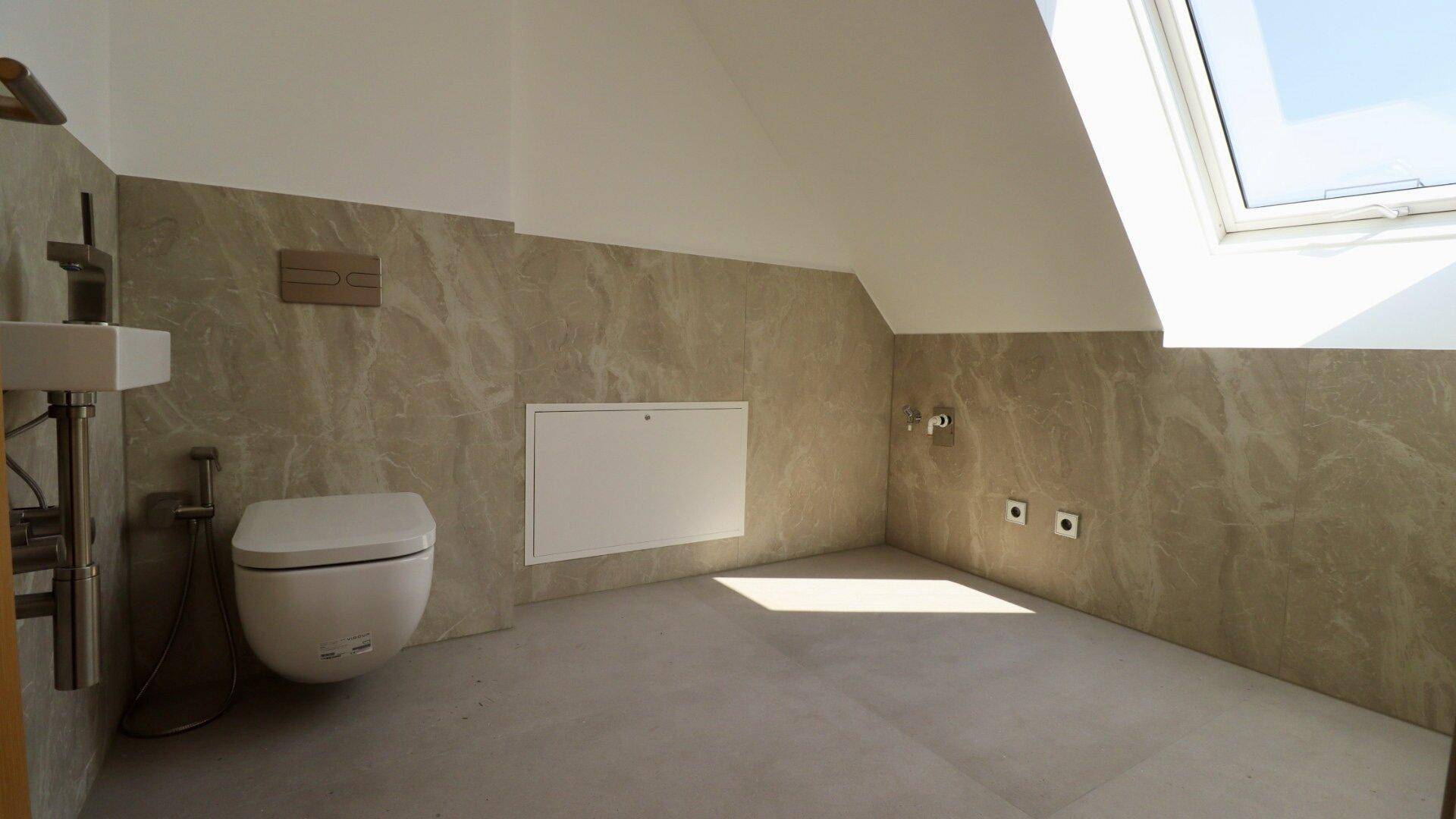 Helles Gäste-WC im Dachgeschoss mit Wand-WC, Dachschräge und viel natürlichem Licht durch das Fenster.