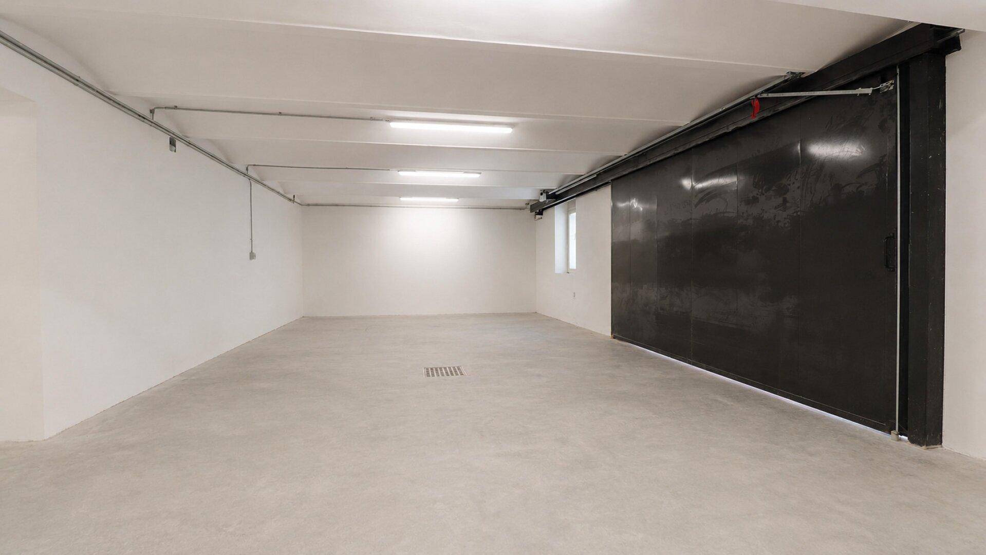 Geräumiger, leerer Kellerraum mit Betonboden, weißen Wänden und einfacher Beleuchtung.