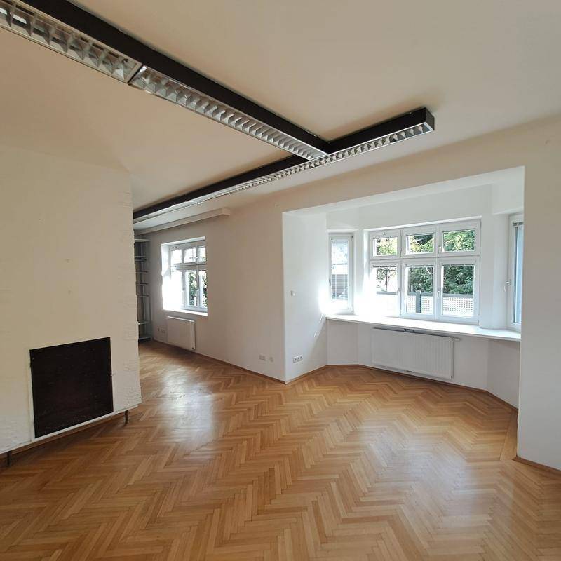 Heller Wohnbereich mit klassischem Fischgrätparkett und breiten Fensterbänken, ideal für individuelle Gestaltung.