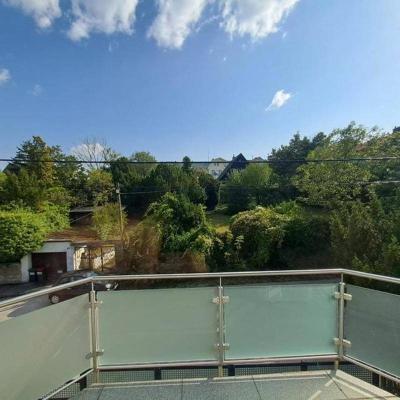 Moderner Balkon mit Glasgeländer bietet einen grünen Ausblick auf die umliegende Natur.