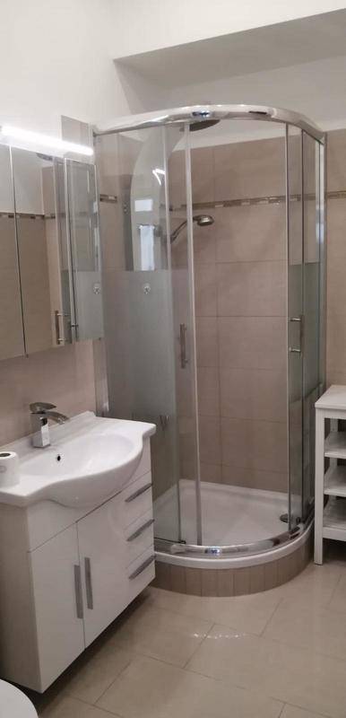 Modernes Badezimmer mit Eckduschkabine, Waschbecken mit Unterschrank und Spiegelschrank.