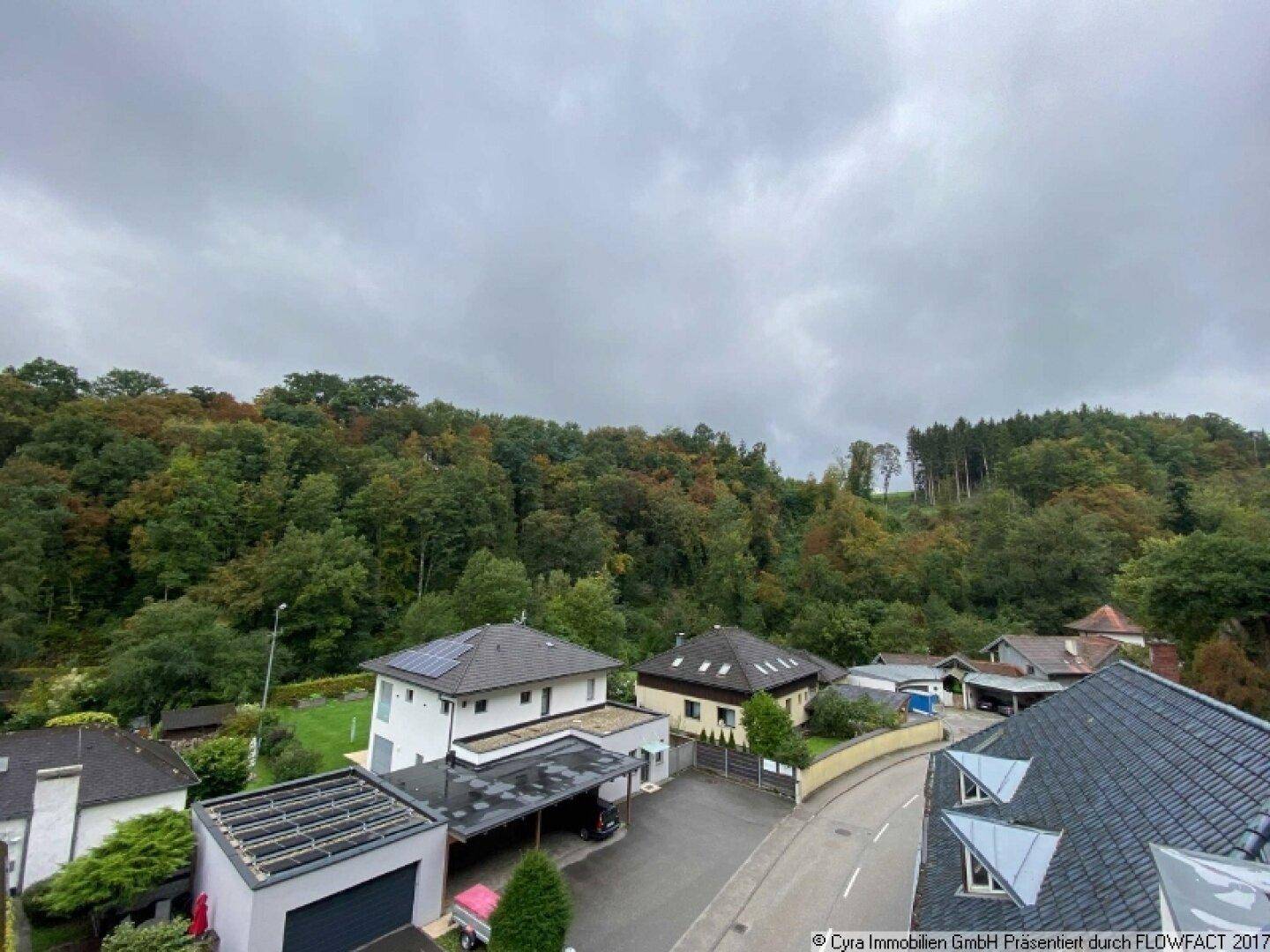 Panoramablick auf die Nachbarschaft mit verschiedenen Wohnhäusern und üppiger Vegetation in der hügeligen Landschaft.