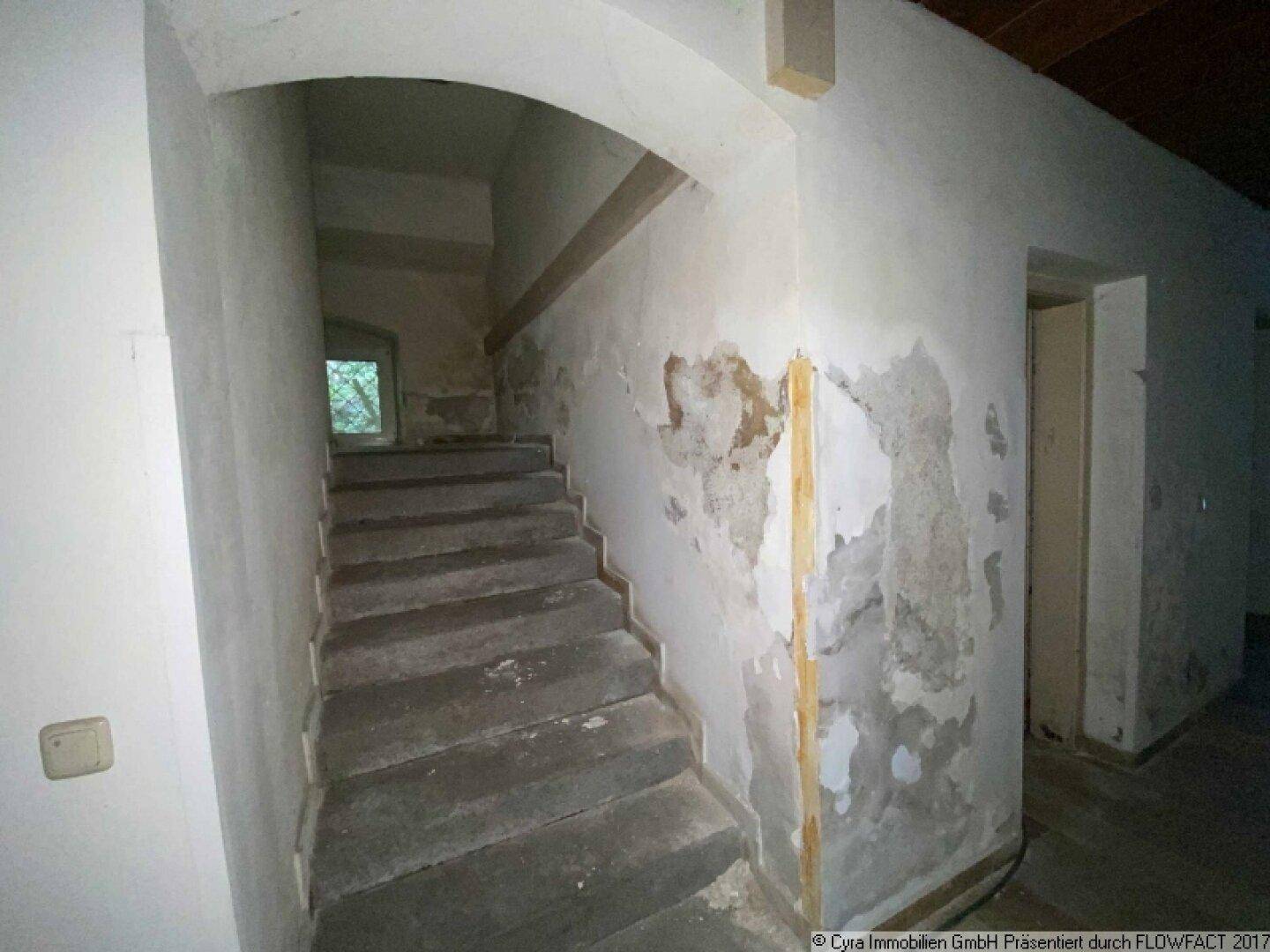 Treppenhaus im Altbau mit abgenutzten Stufen und Wänden, die Renovierungsbedarf zeigen.