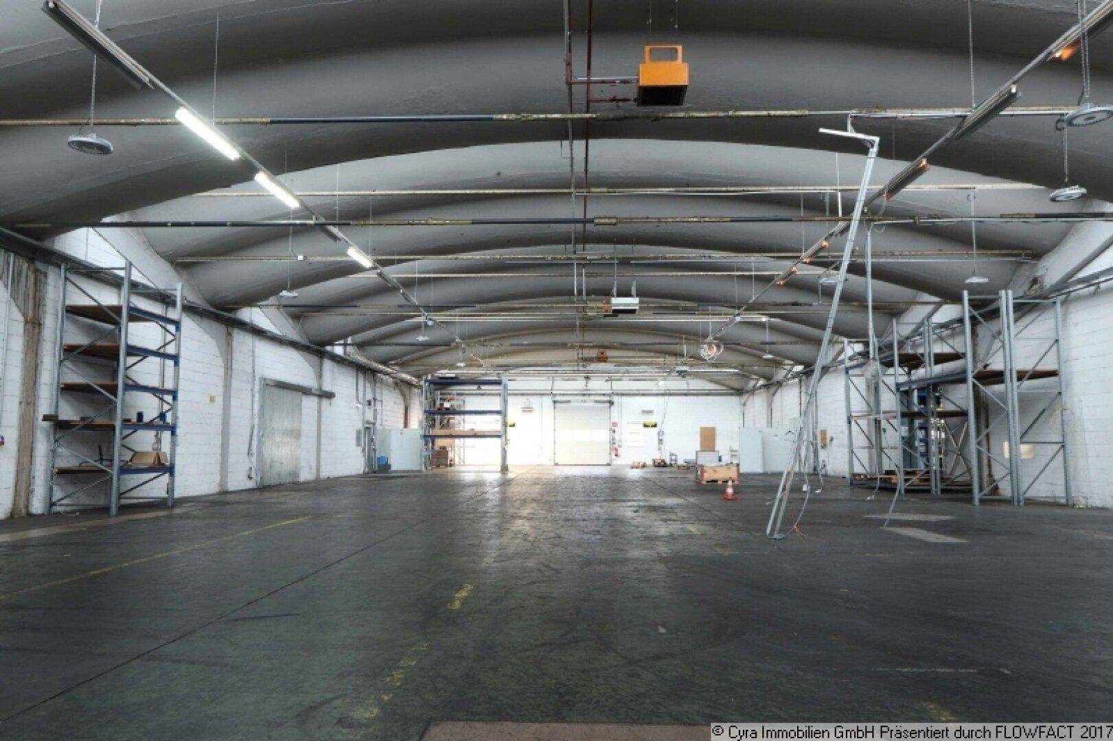 Leere Industriehalle mit hoher gewölbter Decke und Betonboden, bereit für neue Nutzung oder Lagerung.