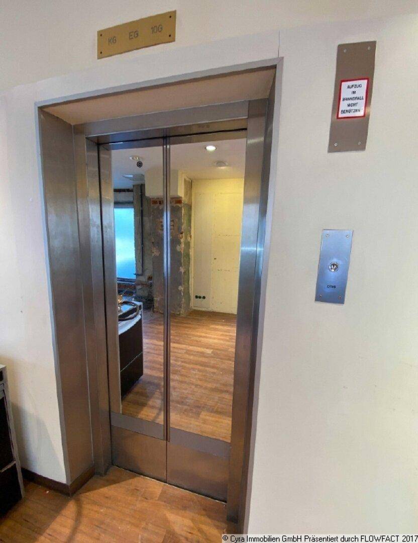 Moderner Aufzug mit Spiegeltüren und Edelstahlverkleidung, der Zugang zu verschiedenen Etagen bietet.