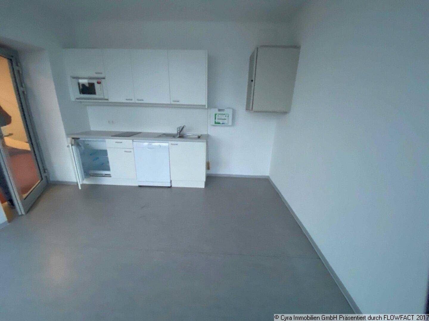 Kleine Einbauküche mit weißen Schränken, Spüle, Geschirrspüler und integriertem Kühlschrank.