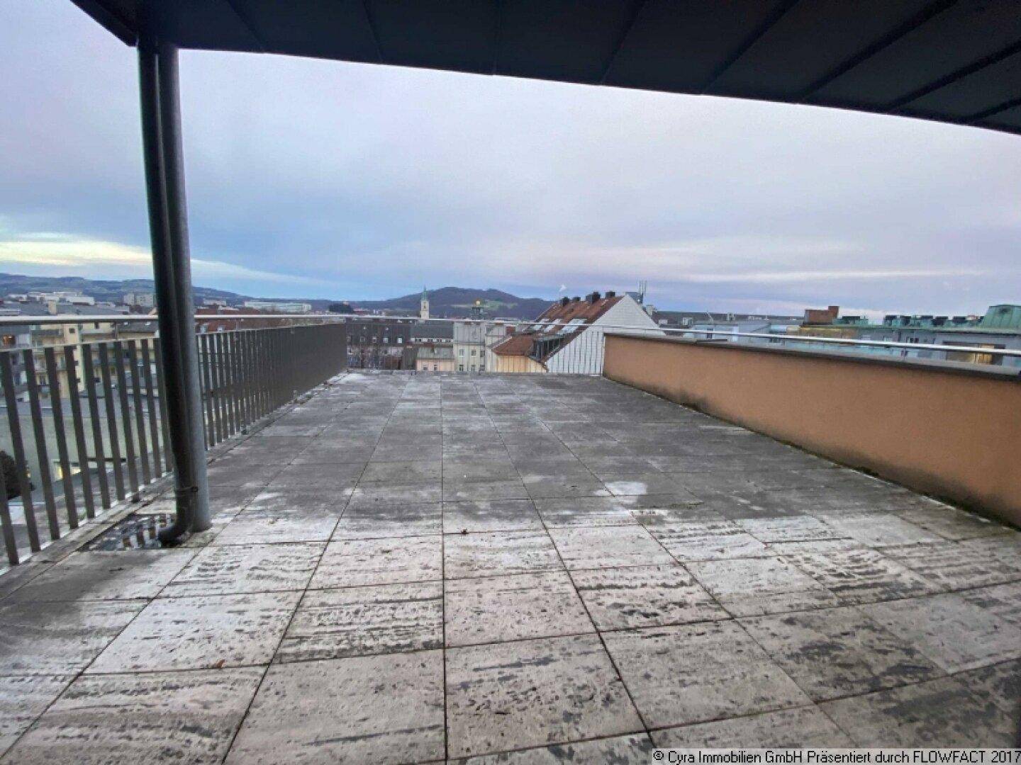 Große, geflieste Dachterrasse mit weitem Blick über die Stadt und die umliegende Landschaft.