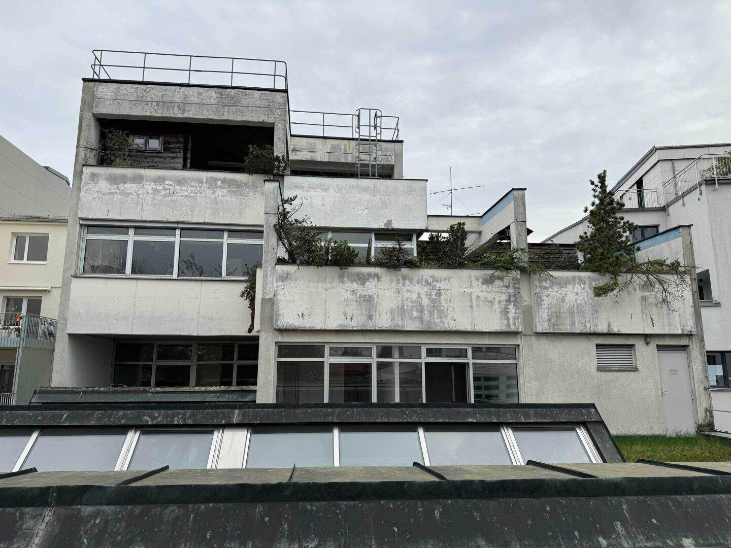 Rückseite eines Gebäudes mit mehreren Terrassen und einer komplexen, gestuften Architektur.