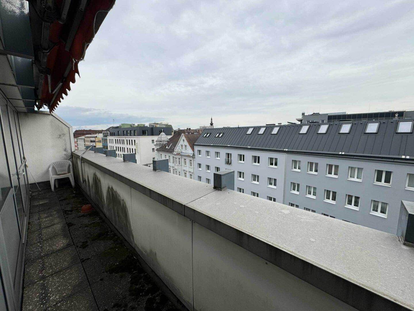 Schmaler Balkon mit Stadtblick und Blick auf umliegende Gebäude.