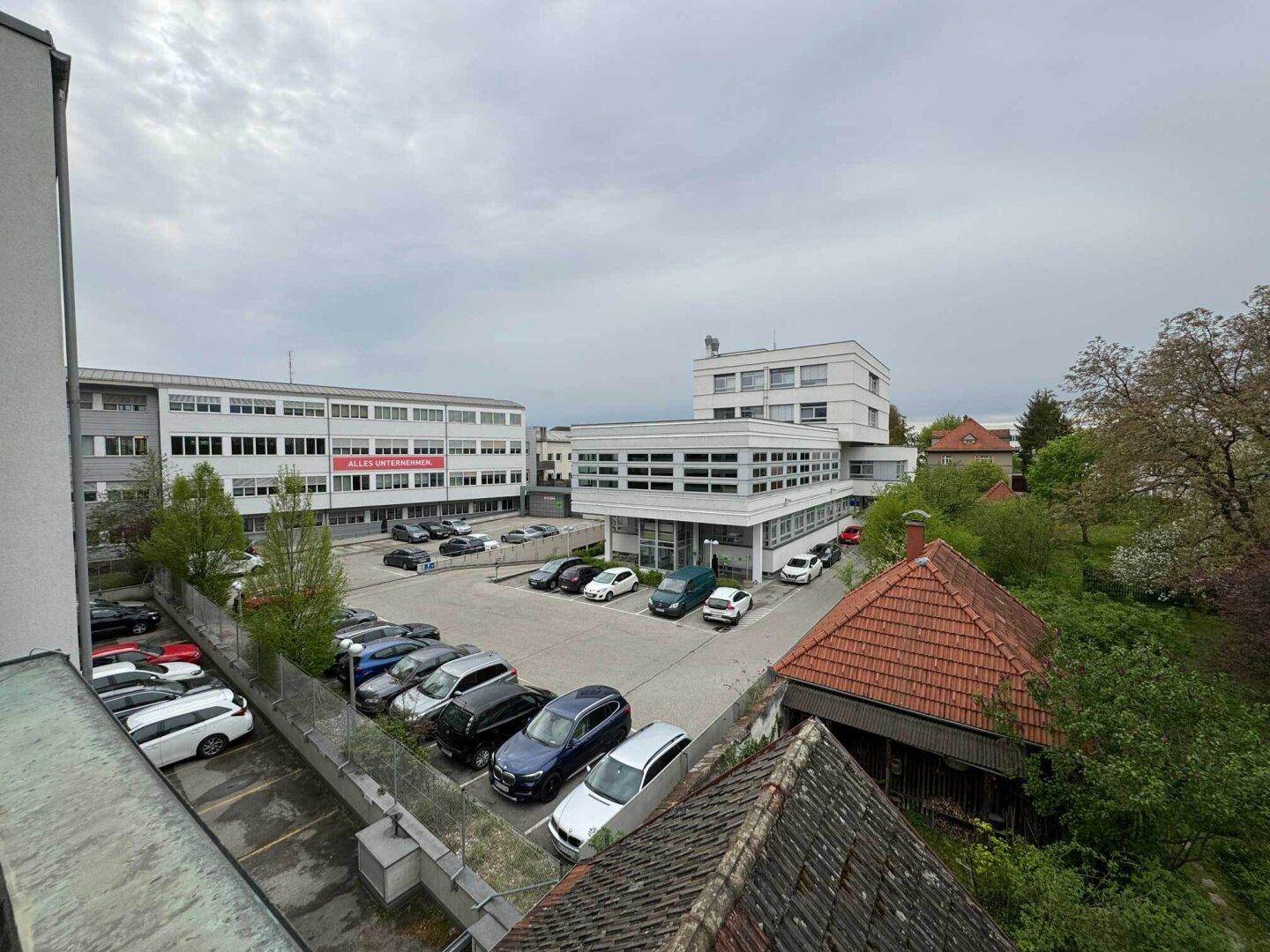 Blick auf einen Parkplatz und umliegende Geschäftsgebäude von oben.