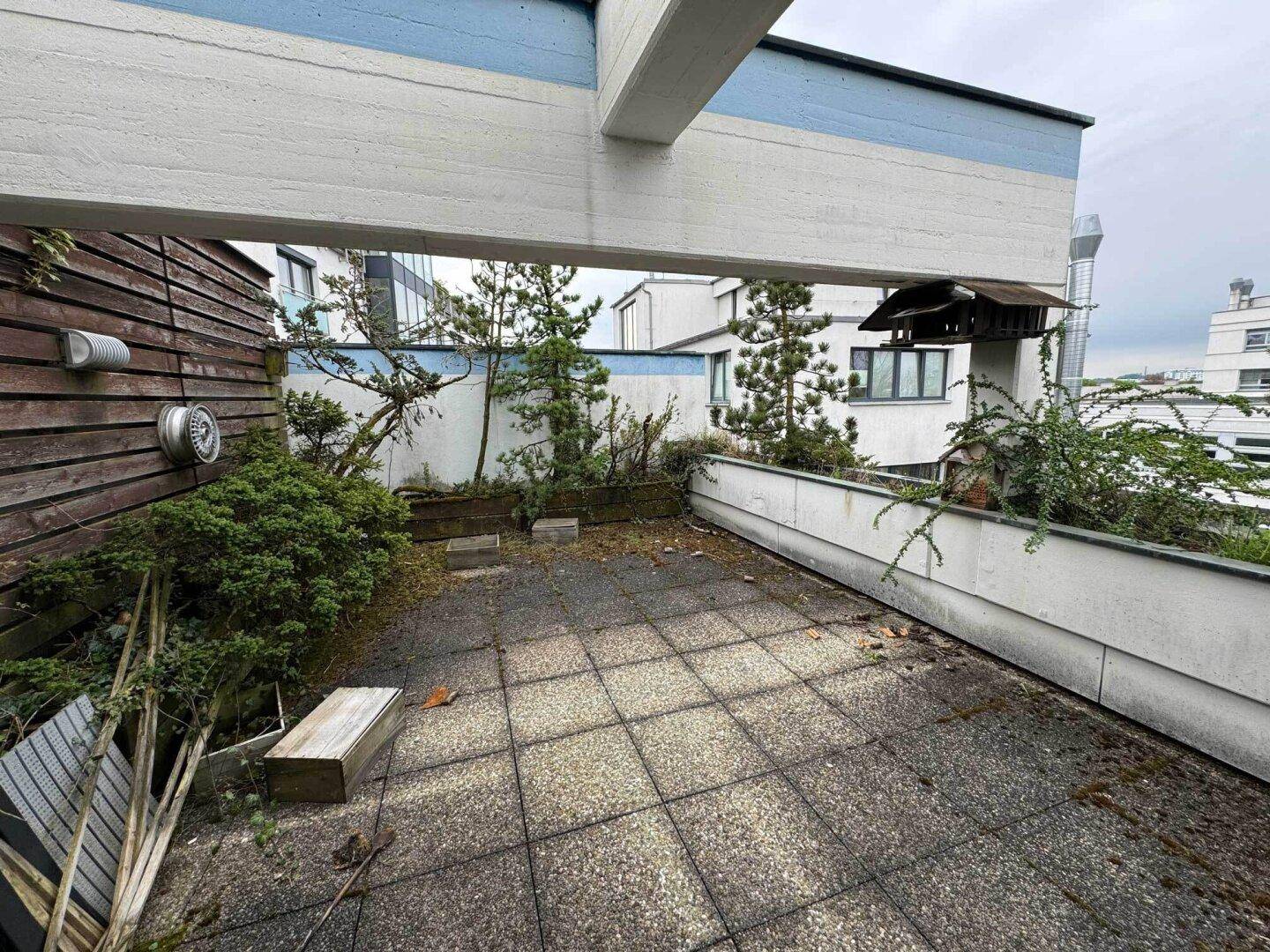 Geräumige Terrasse mit Steinplatten und Blick auf umliegende Gebäude.