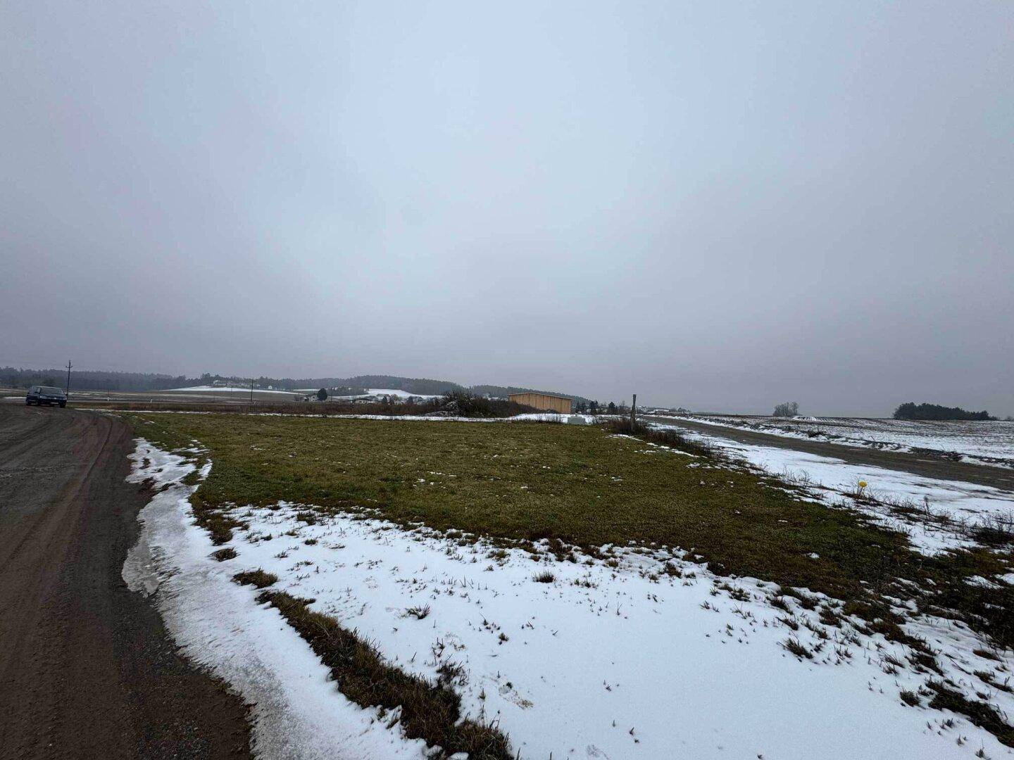 Weitläufiges Grundstück im Winter mit Schneeresten und ländlicher Umgebung unter bewölktem Himmel.