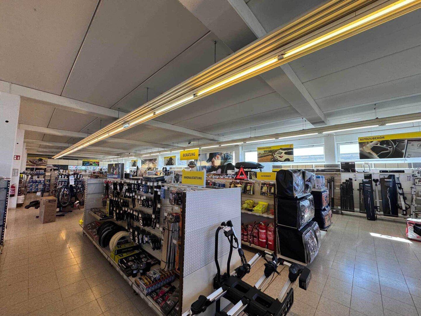 Weitläufiger Ladenbereich mit Produktpräsentationen, Regalen und Deckenbeleuchtung in einem Geschäft.