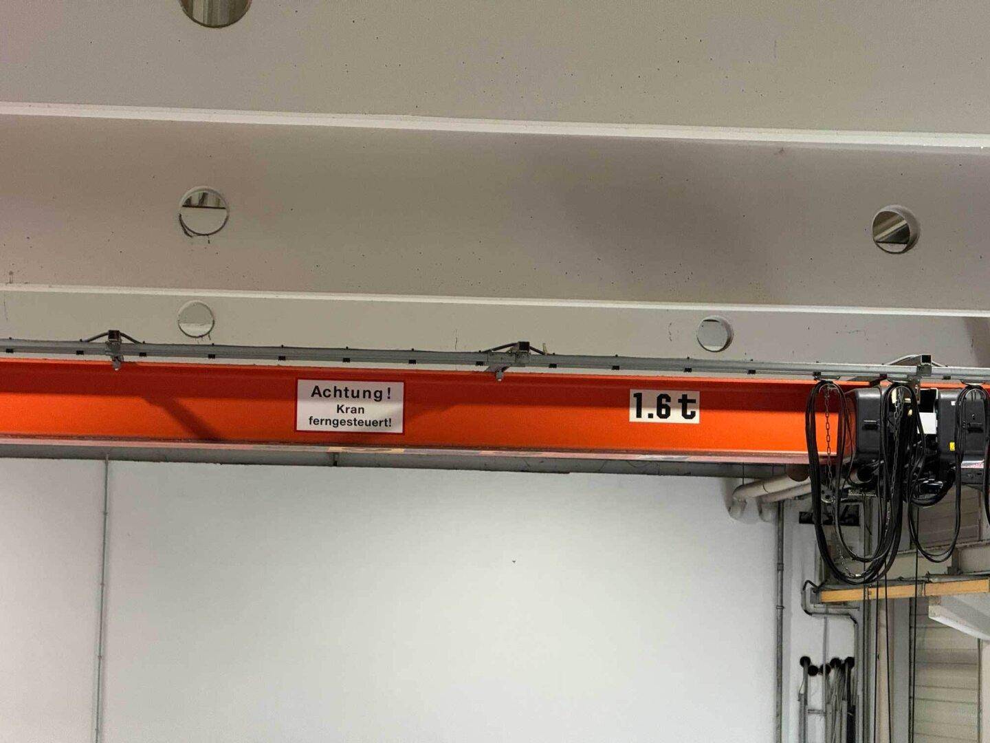 Detailaufnahme eines orangefarbenen Krans mit einer Tragfähigkeit von 1,6 Tonnen in der Industriehalle.