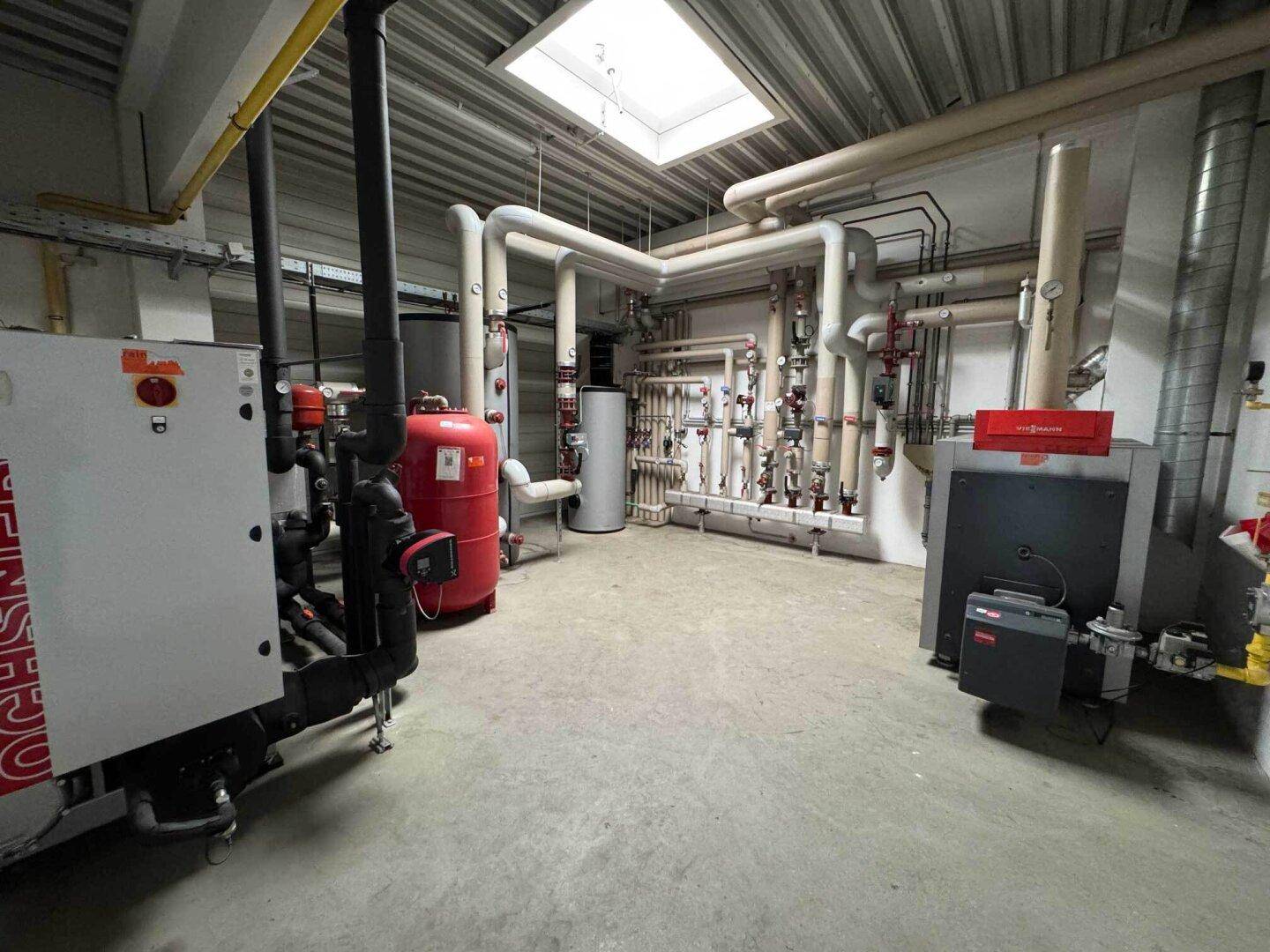 Heizungsraum mit komplexen Rohrleitungen, Warmwasserspeichern und technischen Anlagen.