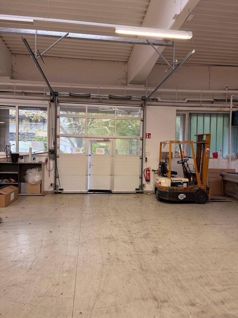 Heller Innenraum mit großem Rolltor, das den Zugang zum Außenbereich ermöglicht.