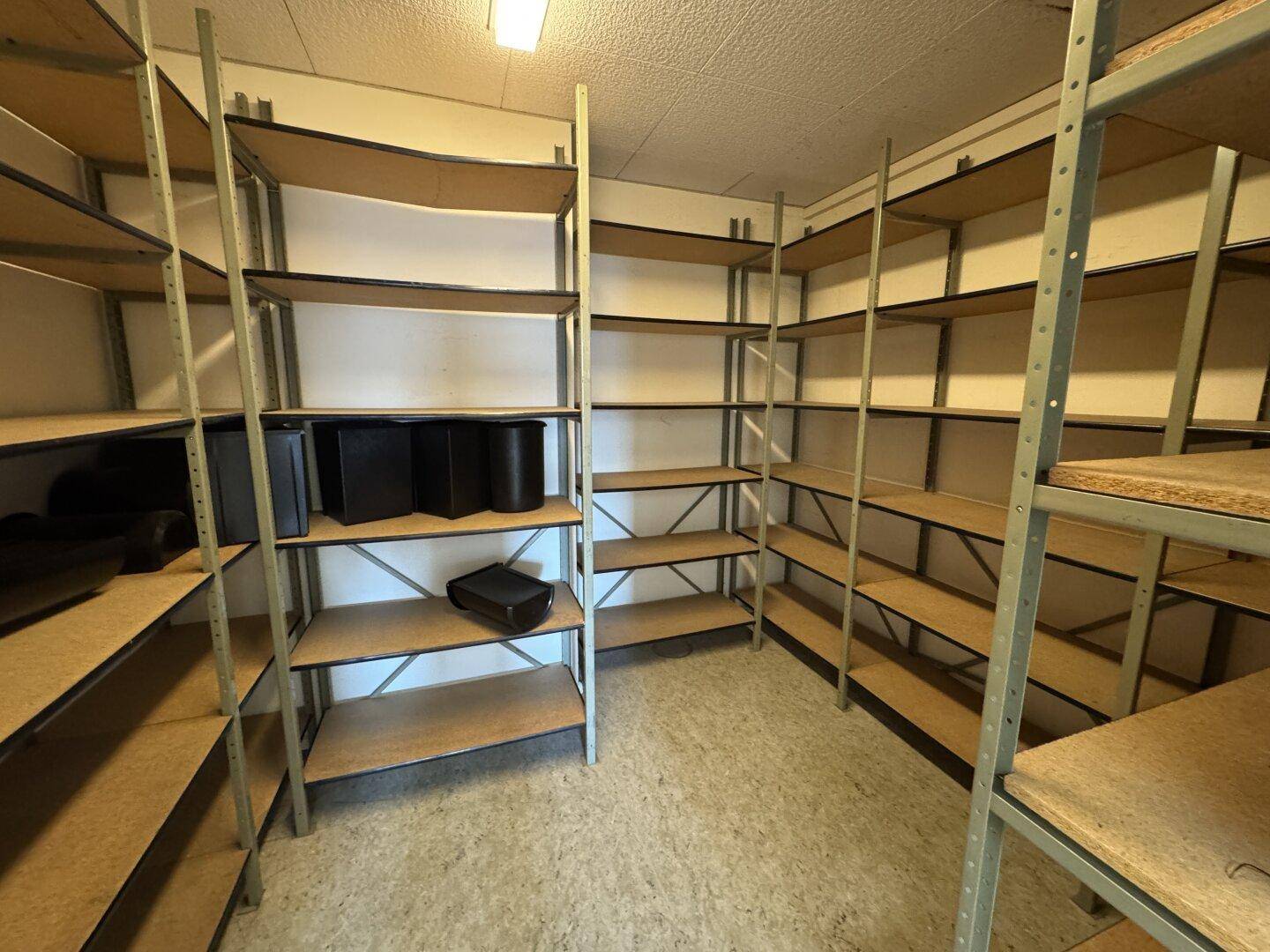 Großer Abstellraum mit zahlreichen Metallregalen und Vinylboden, bietet umfangreiche Lagermöglichkeiten.