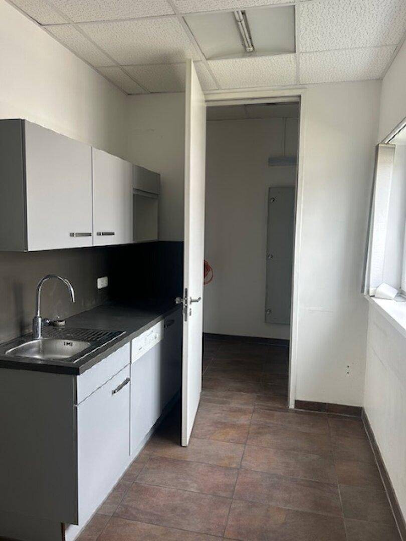 Funktionale Küchenzeile mit grauen Schränken, Spüle, Geschirrspüler und einem Fenster für natürliches Licht.
