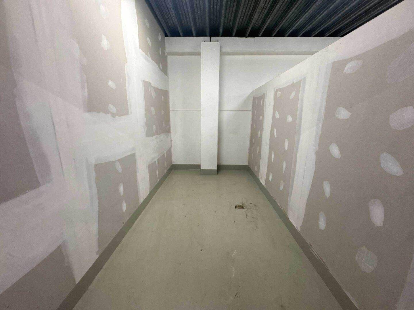 Langer, schmaler Innenraum mit unverputzten Wänden und einem Betonboden, bereit für den Ausbau.